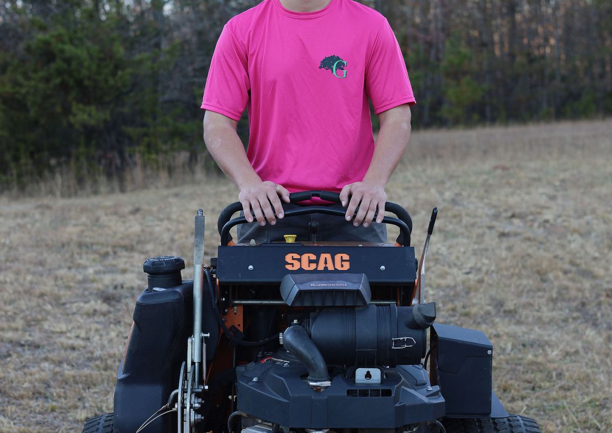 A crew member on a commercial zero-turn mower on a job site.