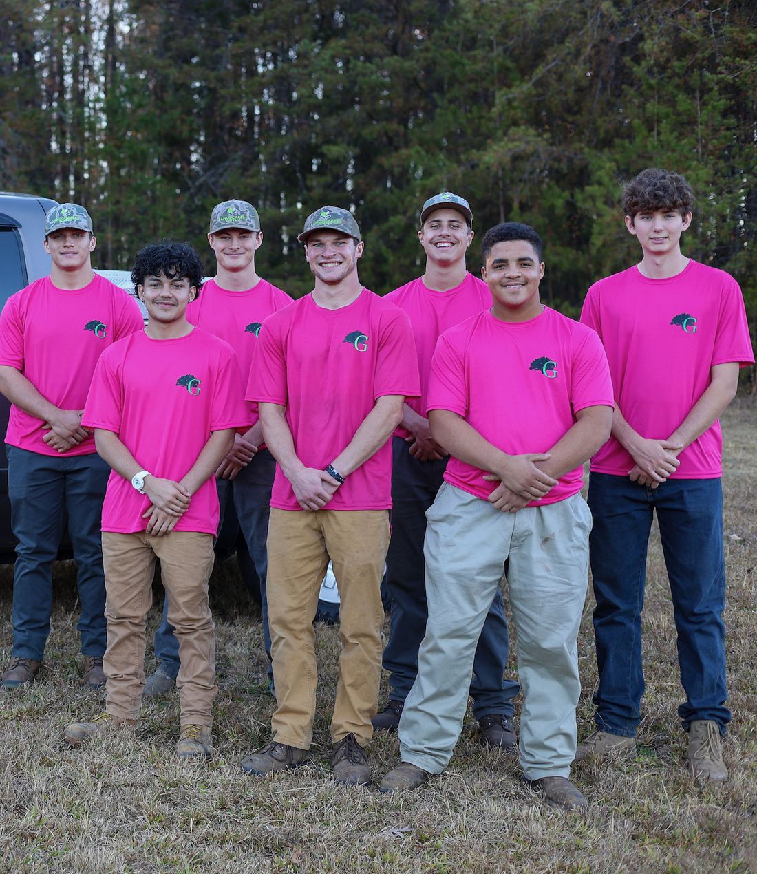 The Greyson&rsquo;s Lawn and Landscape crew in matching fuchsia shirts on a job site.