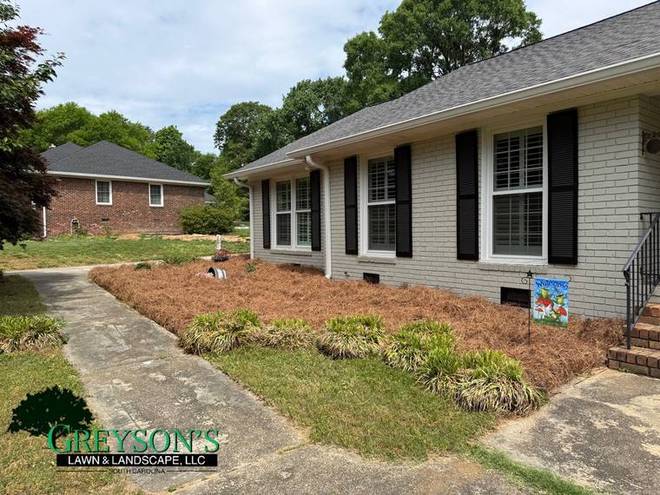A front planting bed with fresh mulch running to the walkway.