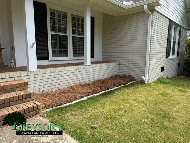 A mulched bed running along the front of a house to the steps.