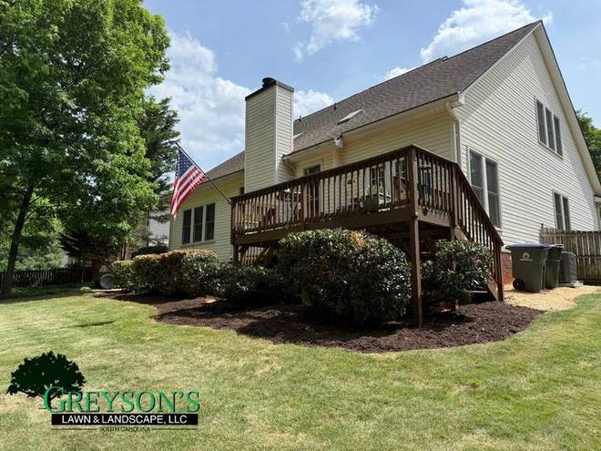 A mulched planting bed wrapping around a rear deck.