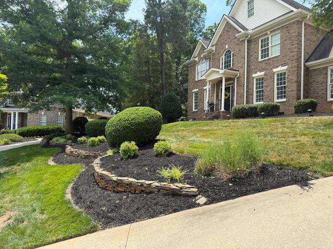 A terraced planting bed with a stone retaining border and clipped shrubs.