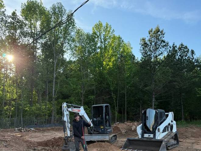 A mini excavator setting boulders into a landscaped area.