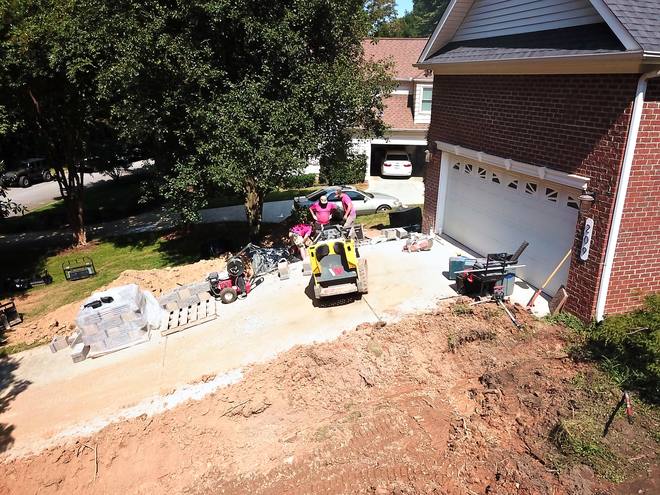 A graded dirt yard beside a driveway with the loader and crew at work.