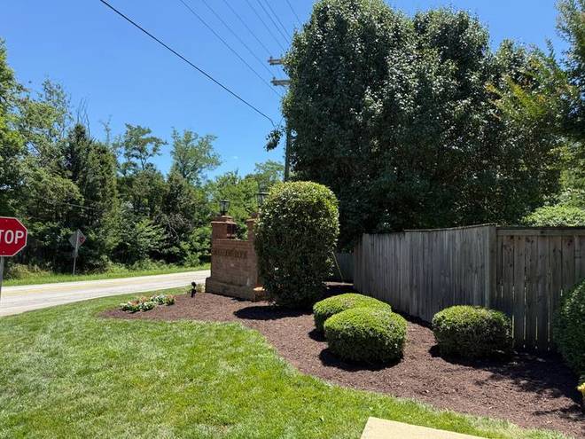 A brick neighbourhood entrance with a mulched bed and clipped shrubs.