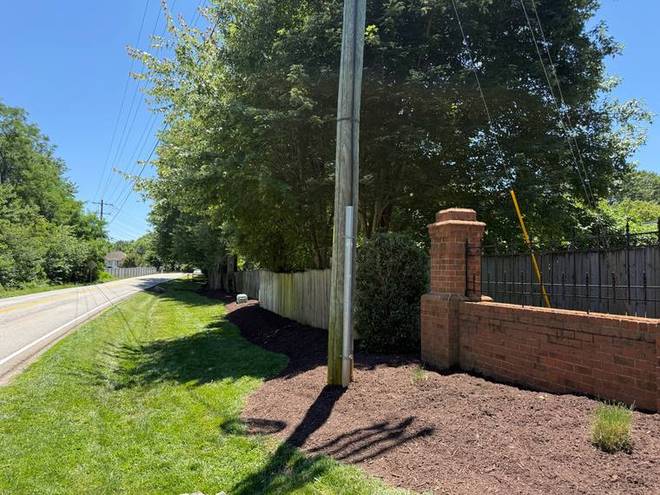 A mulched bed running along a brick entrance wall to the street.