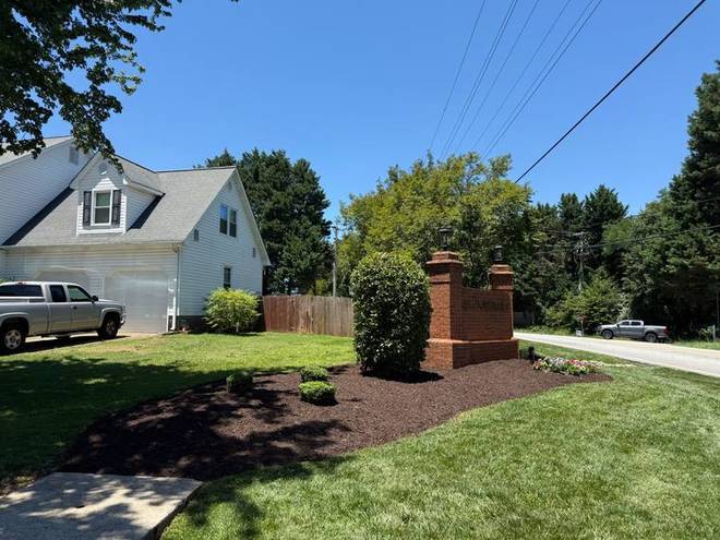 A neighbourhood entrance with clipped shrubs and a clean bed edge.