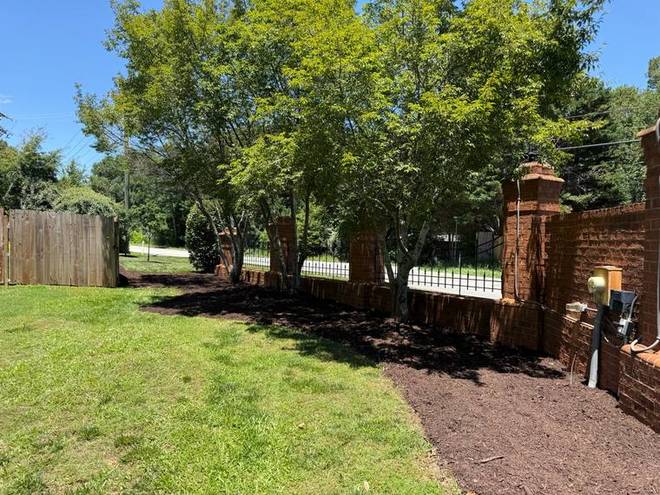 A mulched border running along a fence line at a neighbourhood entrance.