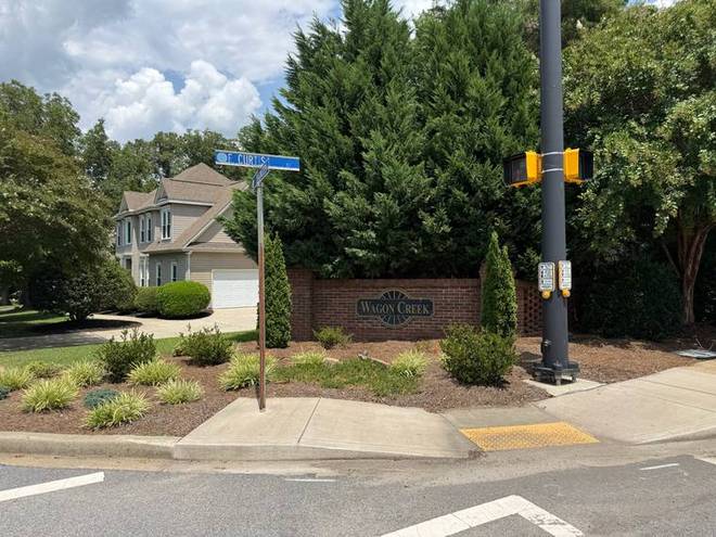 A subdivision entrance monument and landscaped island at a street corner.