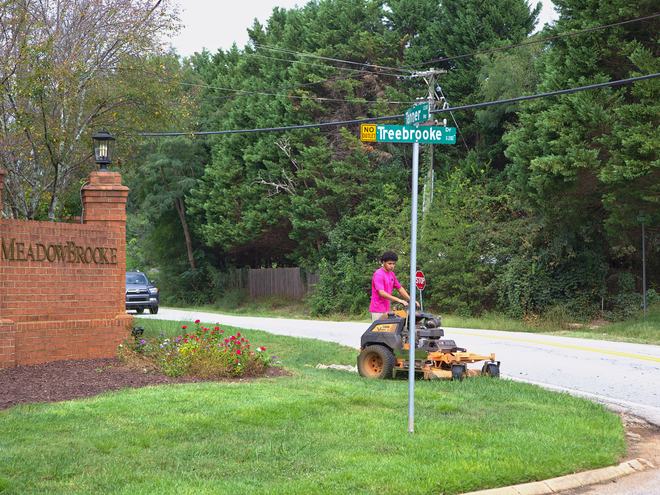 Mowing the turf at a brick subdivision entrance.
