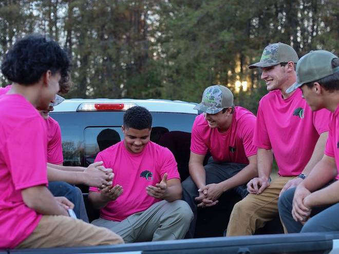 Crew members gathered at the tailgate of a work truck.