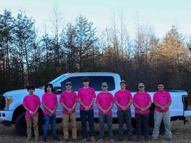The team together in matching shirts beside their trucks.