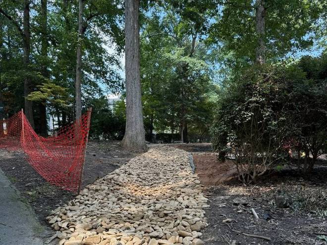 A dry creek bed of river rock built to carry water away from a home.