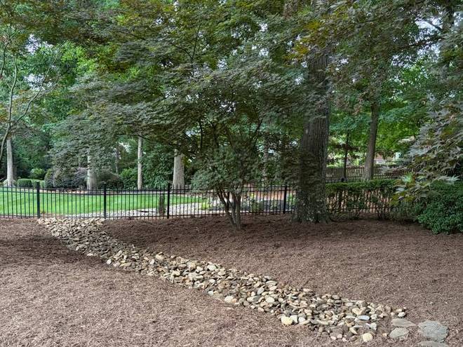 A dry creek bed running through a wooded section of a property.