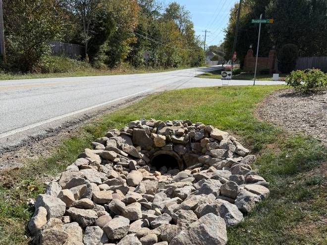 A rock-lined drainage basin built into a lawn to collect storm water.
