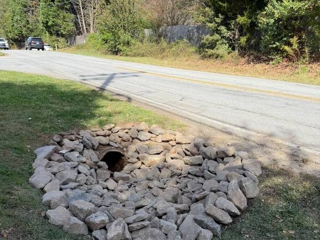 A stone drainage basin set at the low point of a yard.