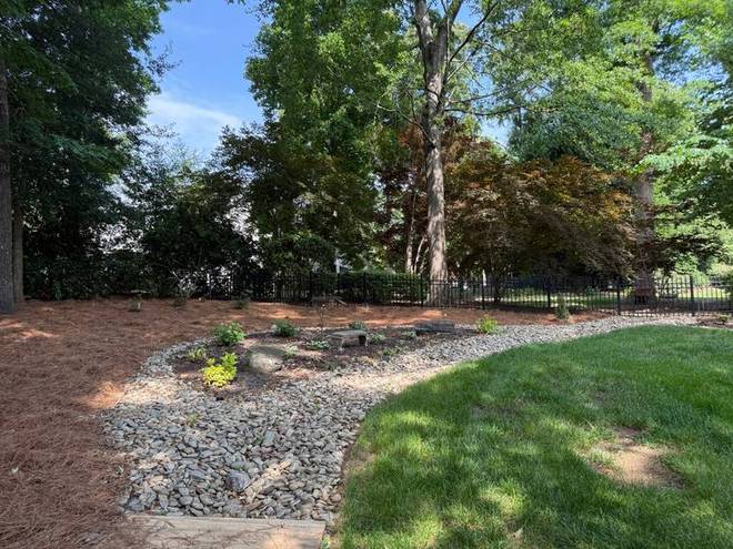 A river rock drainage bed running through a landscaped area.