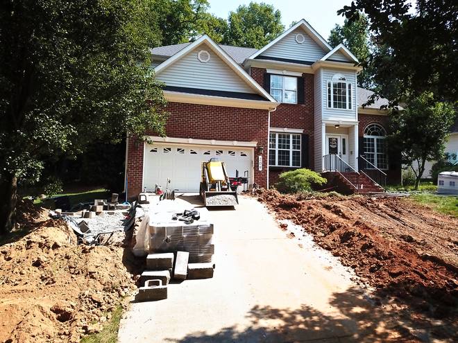 Aerial view of a trench excavated through a front yard toward the driveway.