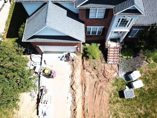 Top-down view of a drainage trench running along the side of a house.