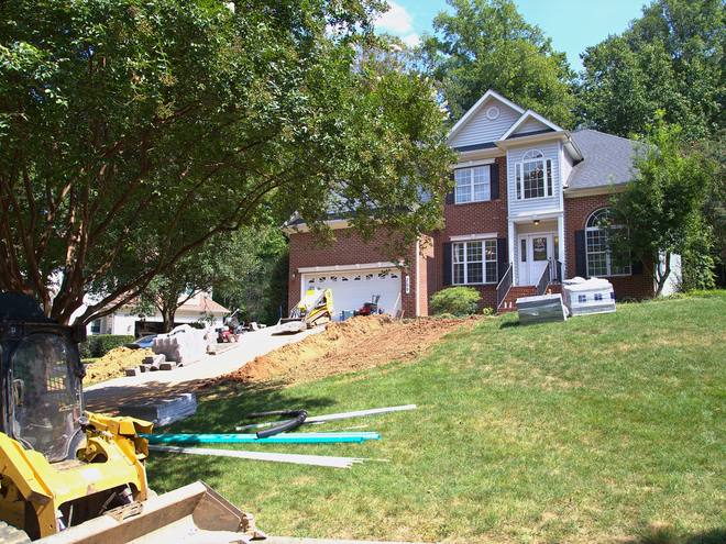 Drainage pipe laid out across a front lawn ahead of trenching.