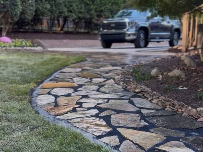 A flagstone walkway running from a driveway toward a home.