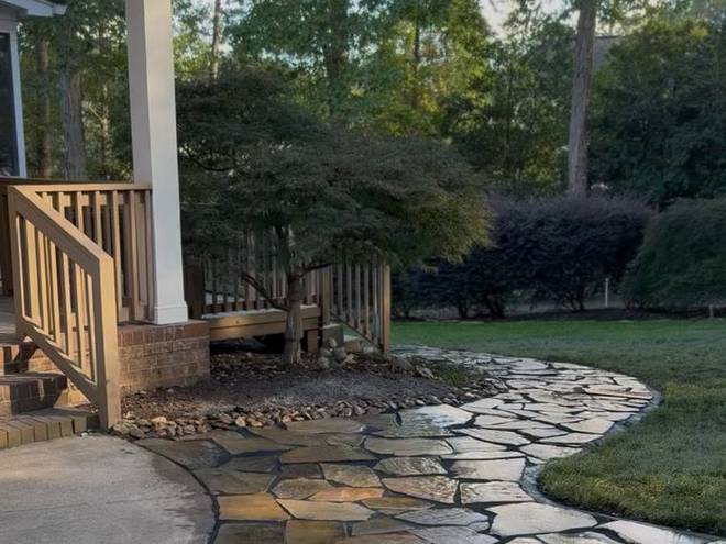 A flagstone path curving around the side of a house to a porch.