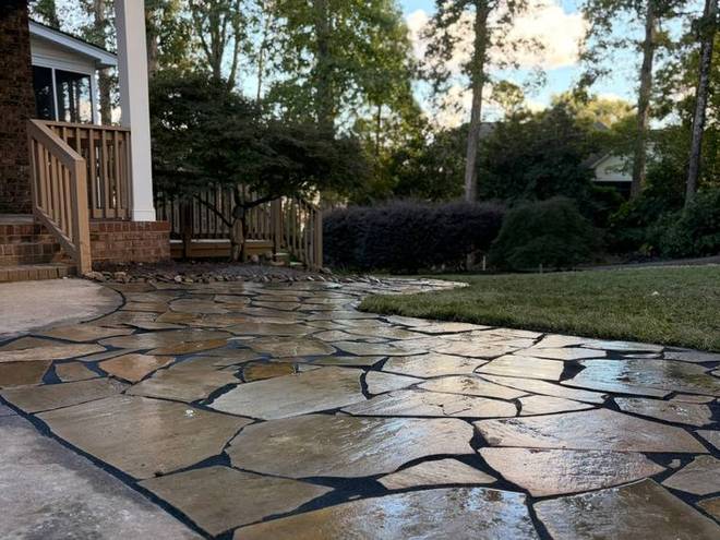 A finished flagstone patio and walkway laid against a concrete drive.