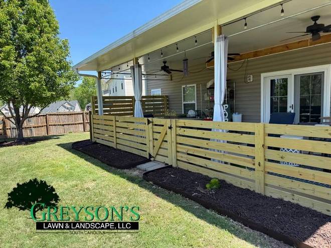 A back patio with a horizontal slat fence and a fresh mulch border.