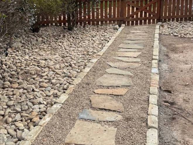 A stepping-stone path set into a river rock border alongside a house.