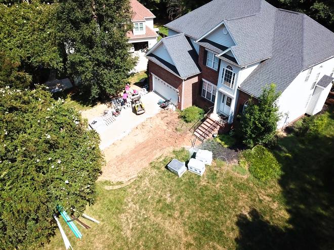 Aerial view of a brick home with pallets of retaining wall block staged on the lawn.