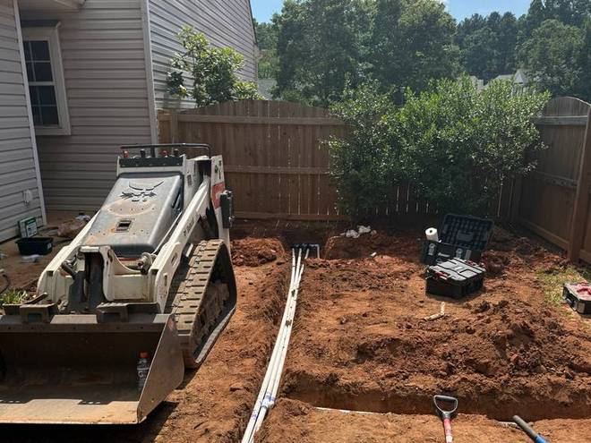 A trench cut across a yard with new irrigation line being laid into it.