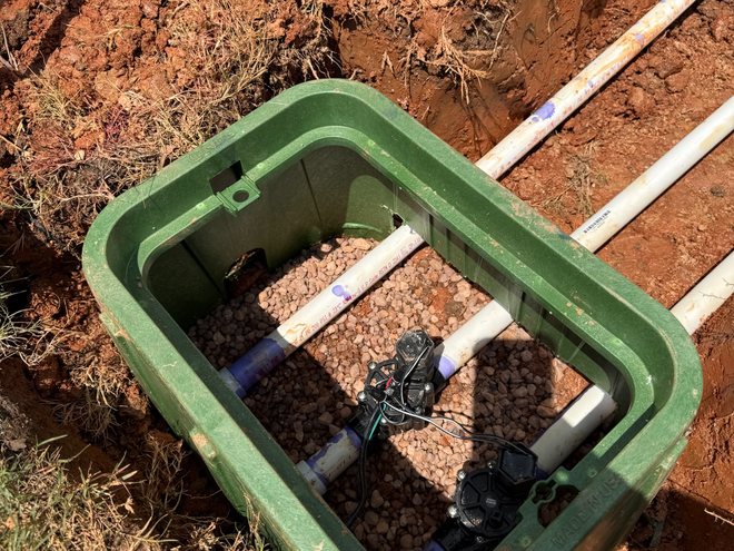 A valve box and manifold being assembled in an open trench.