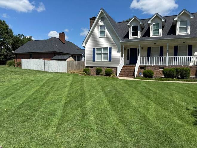 A striped front lawn running up to a house on a sunny day.