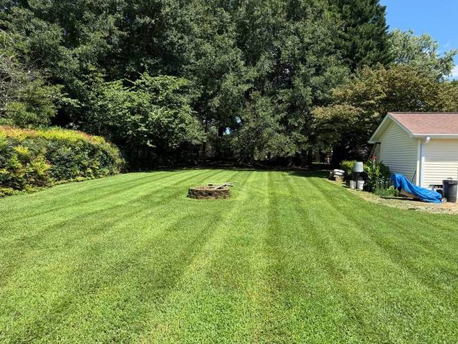 A wide residential lawn cut with clean mowing stripes.