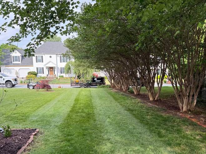 A striped lawn running along a driveway to a garage.