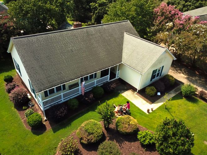 A crew member mowing past the porch of a home, seen from above.