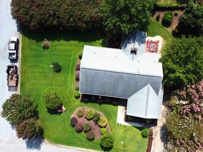 Top-down view of a home with fresh mowing lines and mulched shrub beds.