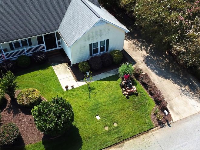 Aerial view of a crew member mowing a landscaped front yard.