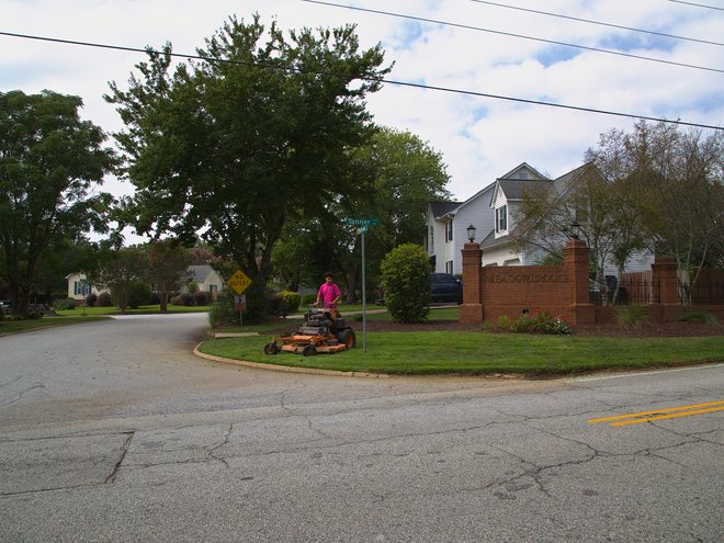 Mowing the lawn at a neighborhood entrance island.