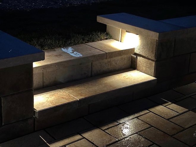 Recessed lights washing down a flight of paver steps after dark.