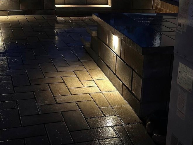 Step and wall lighting picking out the level changes on a patio at night.