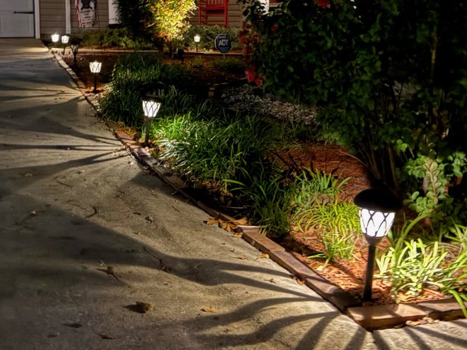 Path lights and a tree uplight along a front walk at night.