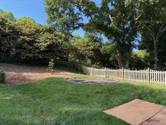 A back yard of freshly laid sod with a new mulch bed along the fence.