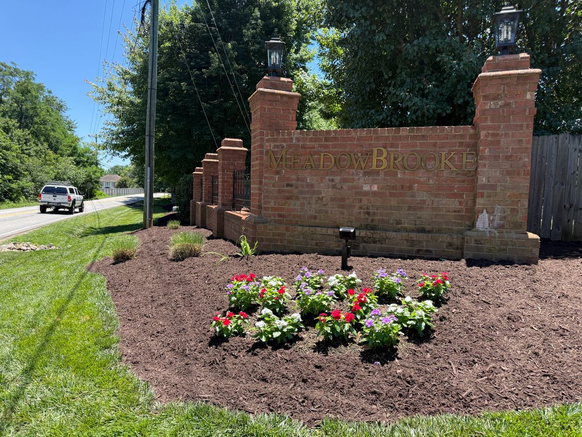 A brick neighbourhood entrance with a fresh flower bed and mulched border.