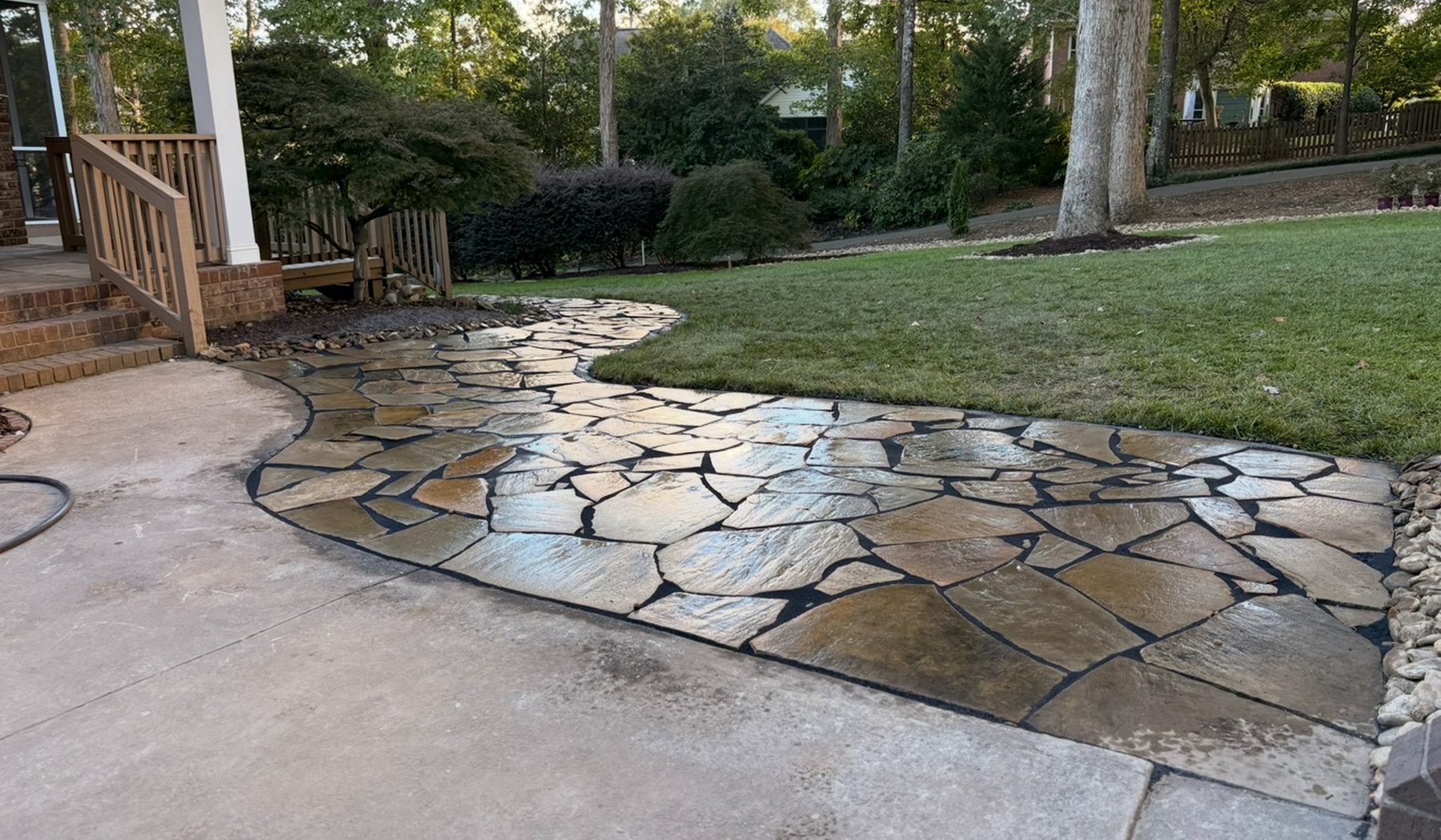 A finished flagstone patio and walkway laid into a back lawn.