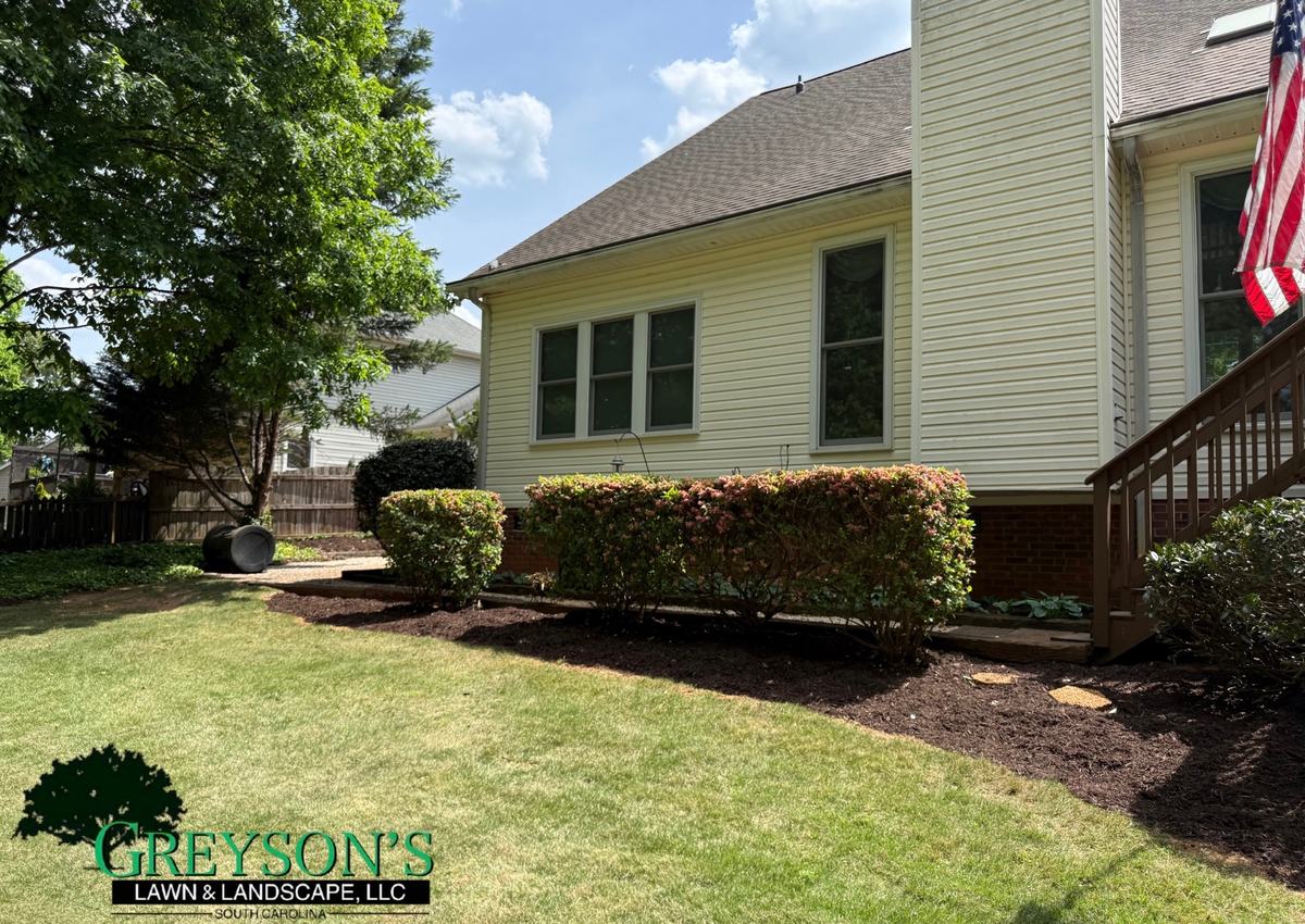 A freshly mulched bed with a clean cut edge running along a home.