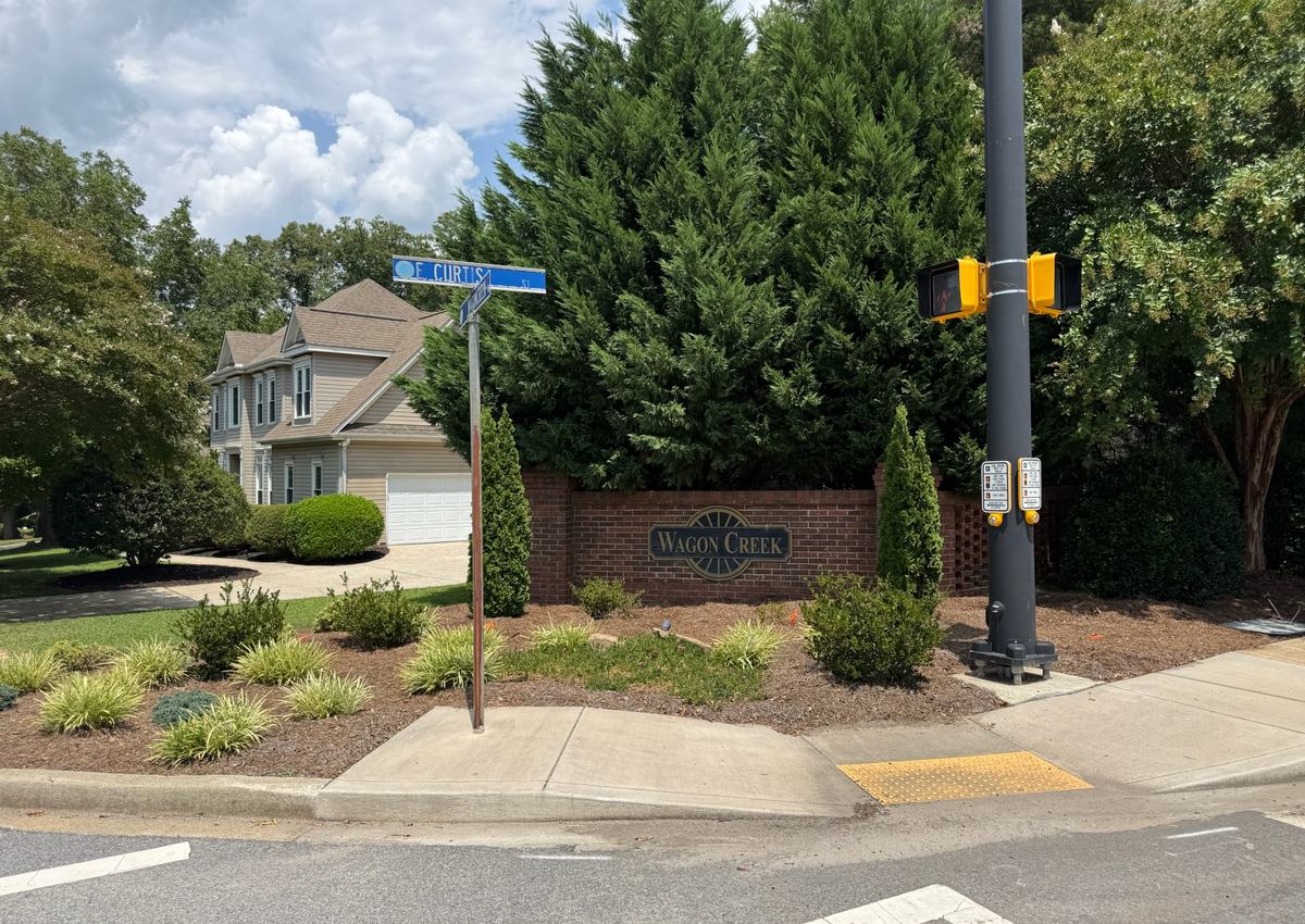 A subdivision entrance monument and landscaped island at a street corner.
