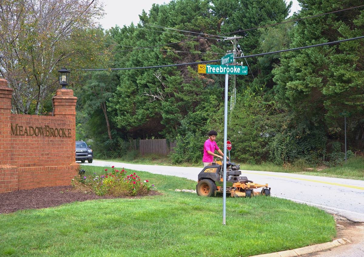 Mowing the turf at a brick subdivision entrance.