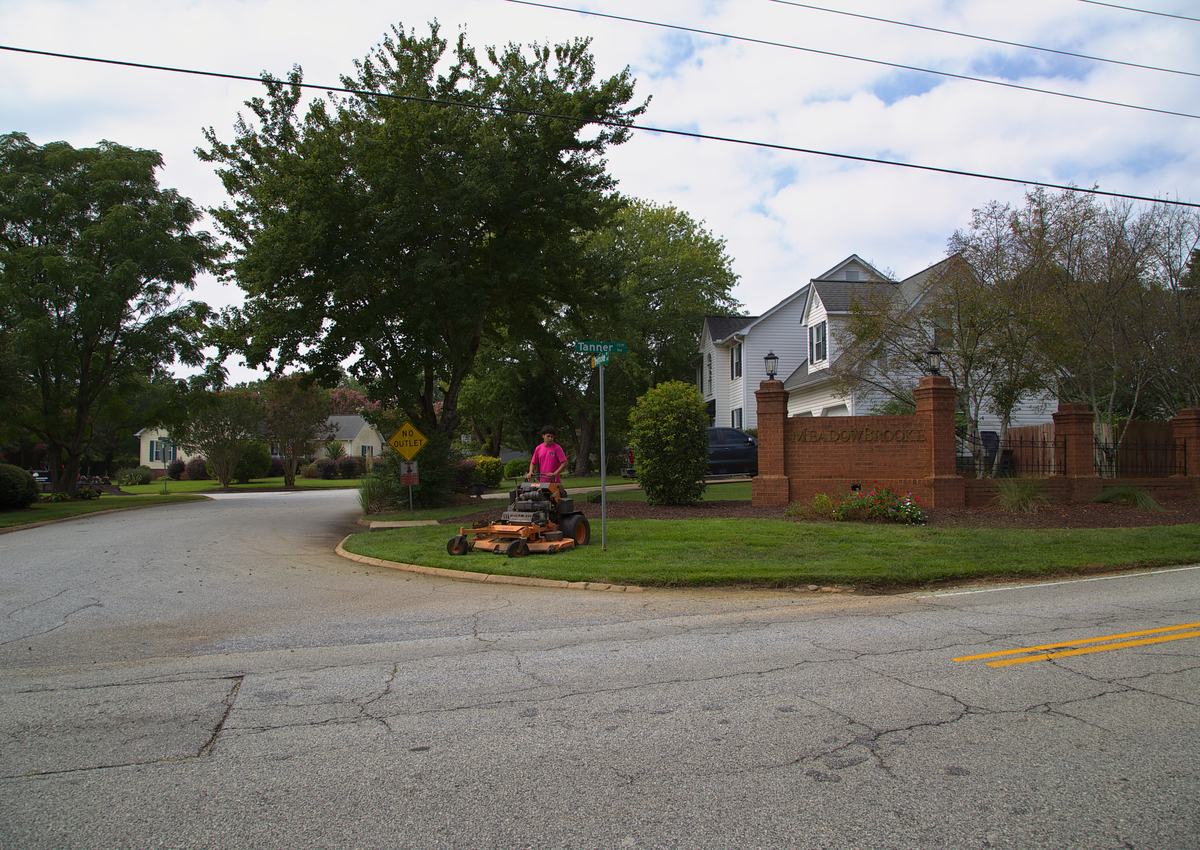 Mowing the lawn at a neighborhood entrance.