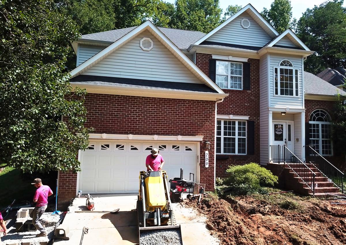 Excavating the front of a home with a compact loader.